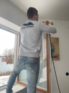 Technik při seřizování plastového okna a kontrole těsnění v rámci servisu oken pro zlepšení těsnosti a snížení tepelných ztrát.